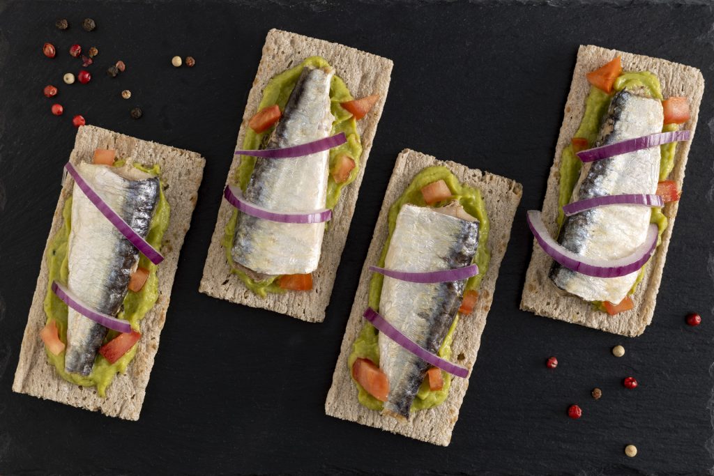 Aperitivo con sardinas en lata en forma de tosta con guacamole