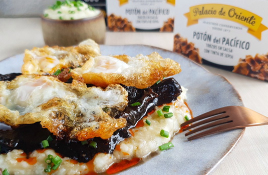 Trozos de potón con tinta de sepia y huevos fritos de codorniz sobre puré de patatas